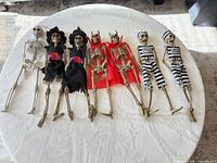 Seven skeleton decorations laid out showing full costumes and sizes
