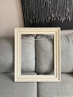 Front view of ornate cream picture frame on sofa