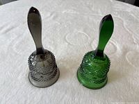 Front view of both green and smoky gray pressed glass bells standing upright