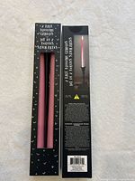 Front and back of boxed pink bleeding taper candles showing two candles per box