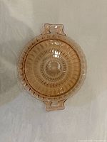 Top view of round pink Depression glass tray showing starburst pattern and handles
