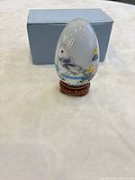 Porcelain egg on wooden stand in front of box