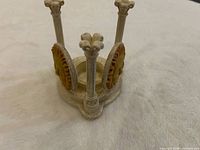 Overall view of resin candle holder showing three columns, sun face plaques and central candle cup