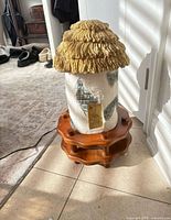 Full lamp assembled showing cottage body, thatched roof shade and wood base