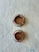 Top view of both round pink ashtrays showing white relief decoration