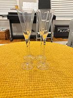Four clear glass champagne flutes standing on table showing full shape