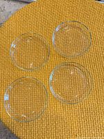 Top view of four clear glass shallow bowls on textured surface