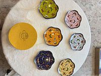 Six scalloped porcelain dishes in assorted colours and yellow storage box