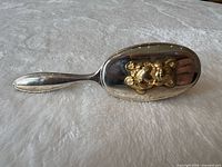 Top view of brush showing silver body and gold teddy ornament