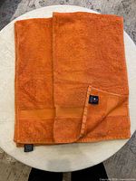Two orange cotton bath towels with Tommy Hilfiger tags visible