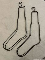 Pair of black metal sock-shaped hangers showing overall form and hook detail