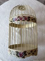 Full view of decorative bird cage showing floral motifs and vertical bars