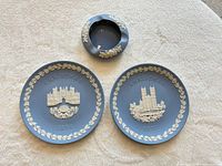 Front view of two blue Jasperware Christmas plates and matching ashtray showing white relief designs