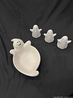 Large ghost candy bowl with three small ghost figurines on black backdrop
