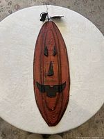 Front view of the elongated wooden pumpkin plaque with metal facial features, stem and hanger visible