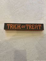 Front view of wooden block sign showing orange text on black background