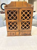 Front view of wooden cabinet with lattice doors and drawers