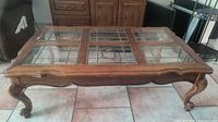 Full view of coffee table showing wood frame, leaded glass top, legs