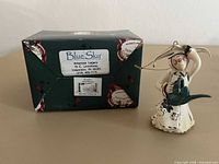 Nun figurine ornament beside original Blue Sky box