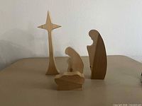 Four pine nativity pieces: star, standing figure, kneeling figure, manger with infant