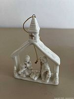 Front view of white porcelain nativity ornament with hanging cord