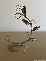 Front view of metal ornament hanger stand showing holly leaf design and base