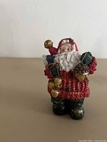 Front view of resin Santa figurine showing attire and accessories