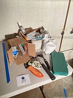 Overall view showing hammers, cutting tools, twine spool, ratchet, green case and box of small hardware on table