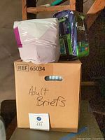 Cardboard box labeled Adult Briefs with two sealed packs on top
