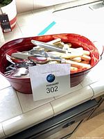 Overall lot view showing red tub filled with cream-handled flatware