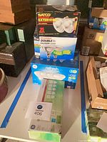Stacked boxes of Satco, Sylvania, GE Refresh LED and GE fluorescent bulbs