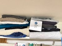 Two stacks of folded women’s clothing on shelf