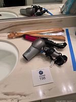 Hair dryer, curling iron and back scratchers on vanity