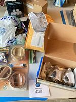 Assorted packaged hardware items on table, including showerheads box, furniture grippers, bulbs and other accessories