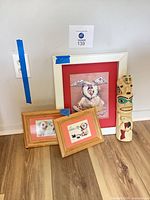 Group view of three framed Inuit prints and one wooden painted totem pole