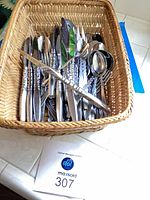 Basket filled with mixed stainless steel flatware pieces