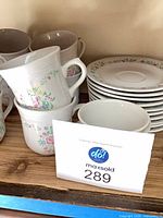 Stacked floral mugs, additional cups, stacked saucers