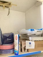 Shelf showing foil containers, stirrer box, Ralphs box, paper plates, napkins and cups