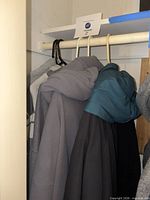 View of several jackets and sweaters hanging on closet rod
