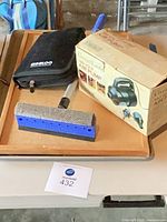 Overview of jump starter case, air pump box, squeegee on cork board atop drip tray