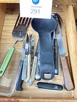 Top view of drawer contents showing knives, spatula, spoon rest, Swiss Army knife