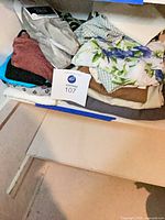Shelf with assorted folded women’s garments and lot tag visible