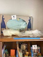 Wedding dress in boxed window display with additional fabric pieces on shelf