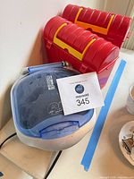 Mini George Foreman grill closed with two red lunch pails beside