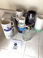 Group of assorted mugs and Batman Forever glass on counter