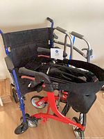 Overview of three mobility aids: blue transport wheelchair, red rollator, silver walker