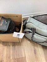 Camcorder in cardboard box alongside fabric carry bag