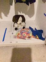 Stuffed dog, printed blanket, blue outfit visible