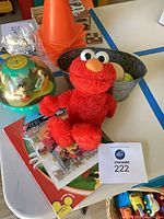 Overall lot showing Elmo plush, chime ball, tub with balls, cone, book and stickers