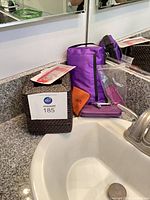 Lot overview showing tissue box cover, purple pouch, wallet and packaging near sink